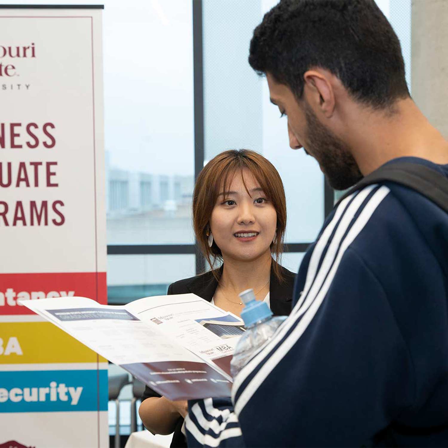 A College of Business professor talks to a student at an open house event.
